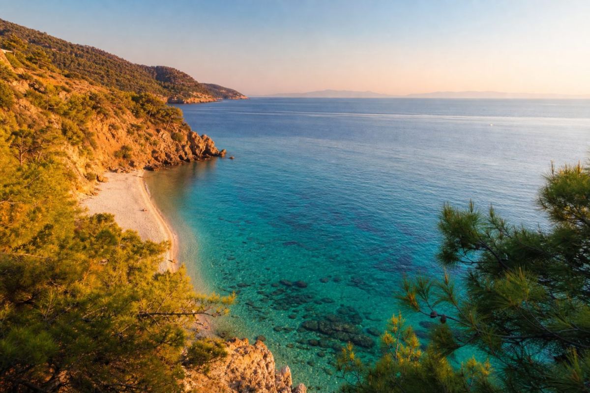 Turkos badvik på Karpathos med ljus sand och gröna pinjeträd ner mot Egeiska havet