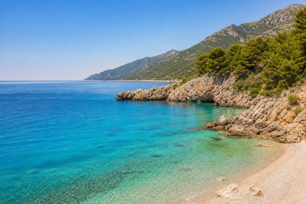 Solig kustvik i Montenegro med turkost Adriatiskt hav, klippstränder och gröna berg i bakgrunden