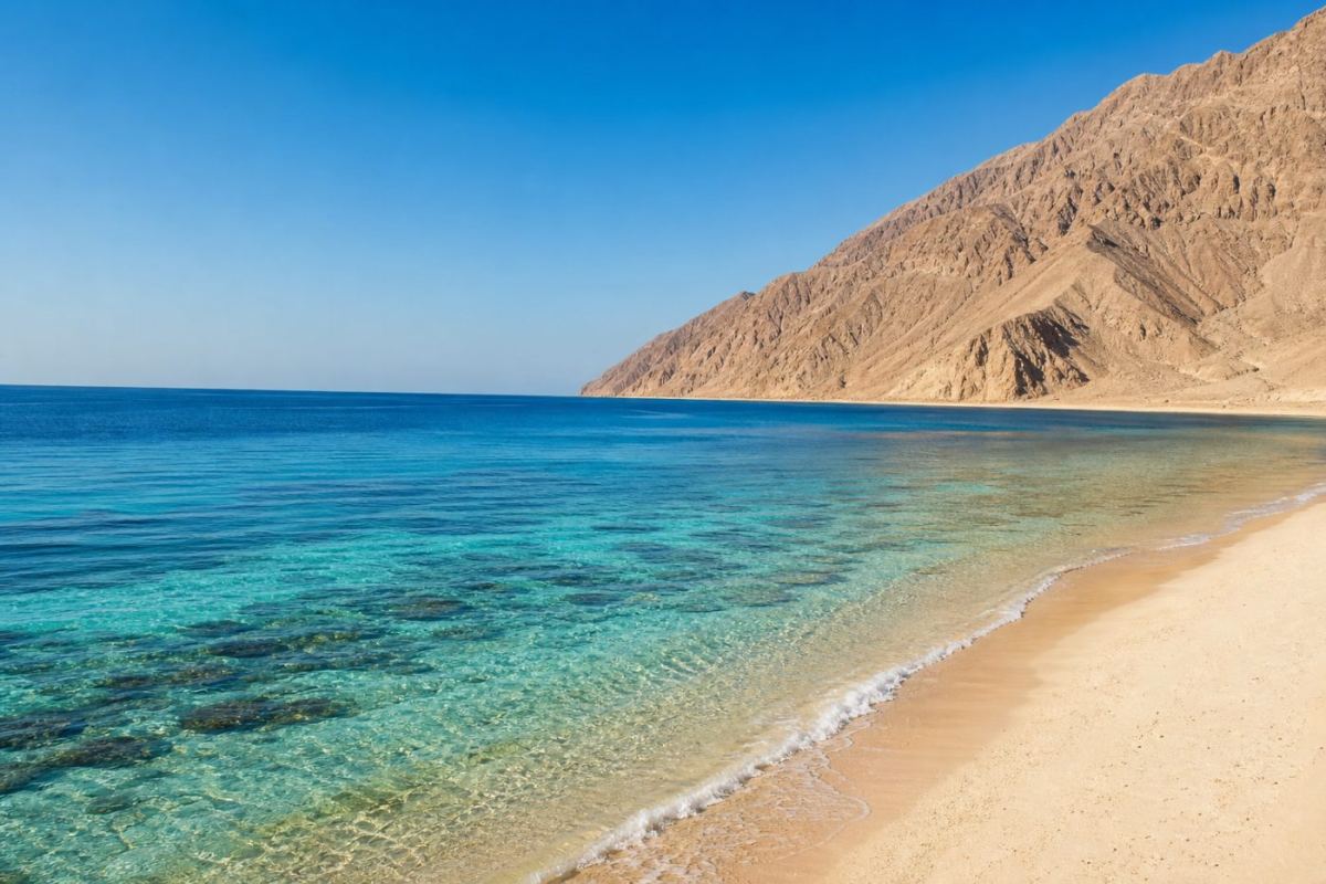 Solig strand med turkost vatten och korallrev vid Röda havet i Sharm el Sheikh